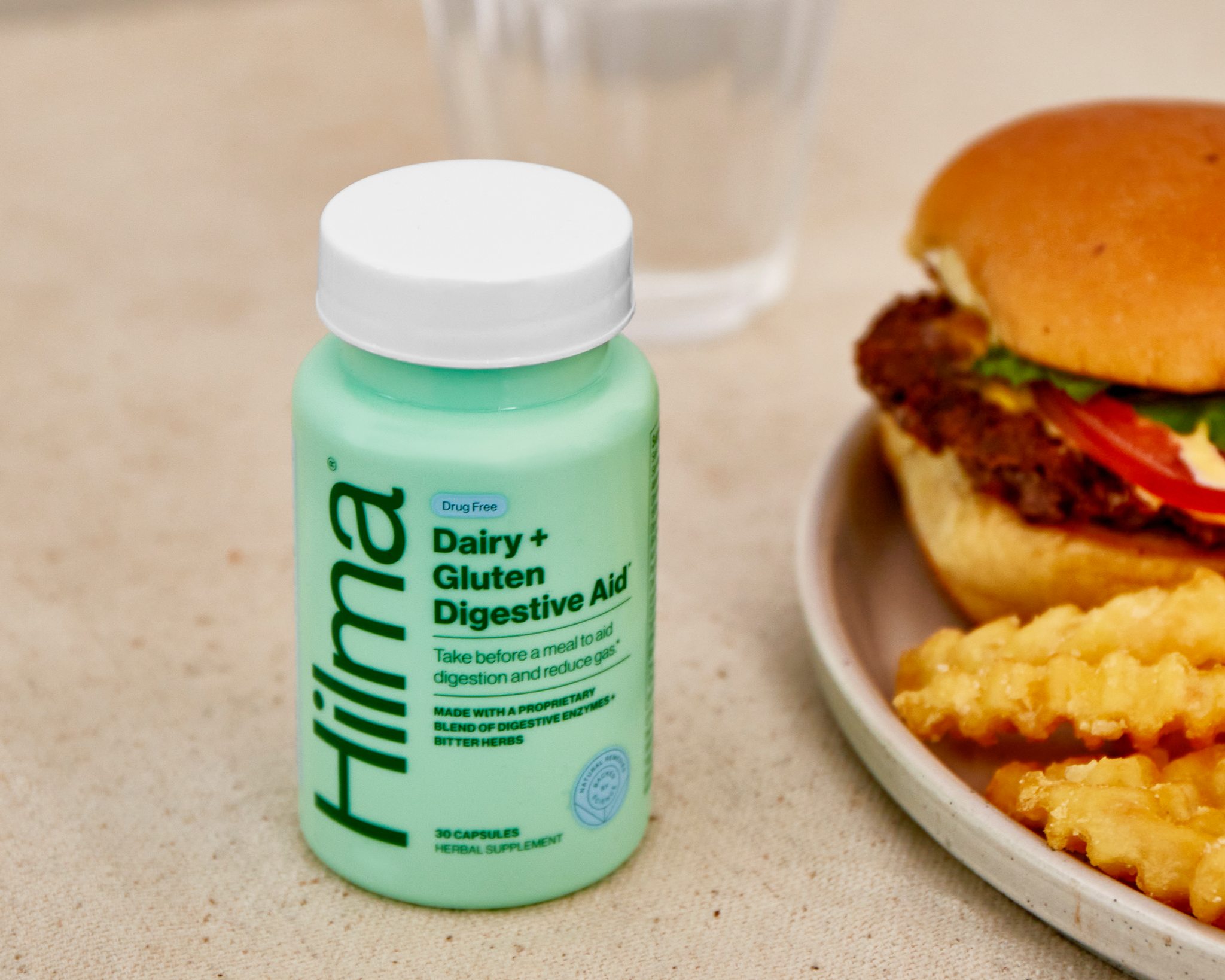 Dairy + Gluten Digestive Aid bottle next to a plate of a cheeseburger + fries