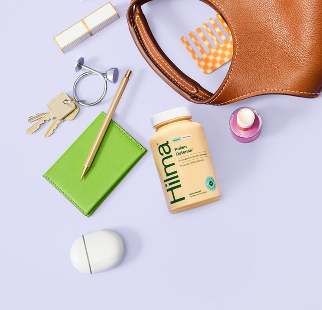 Brown leather pouch with various items on a light purple background