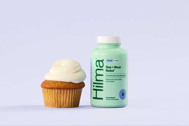 Bottle of Hilma gas + bloat next to a cupcake on a light purple background
