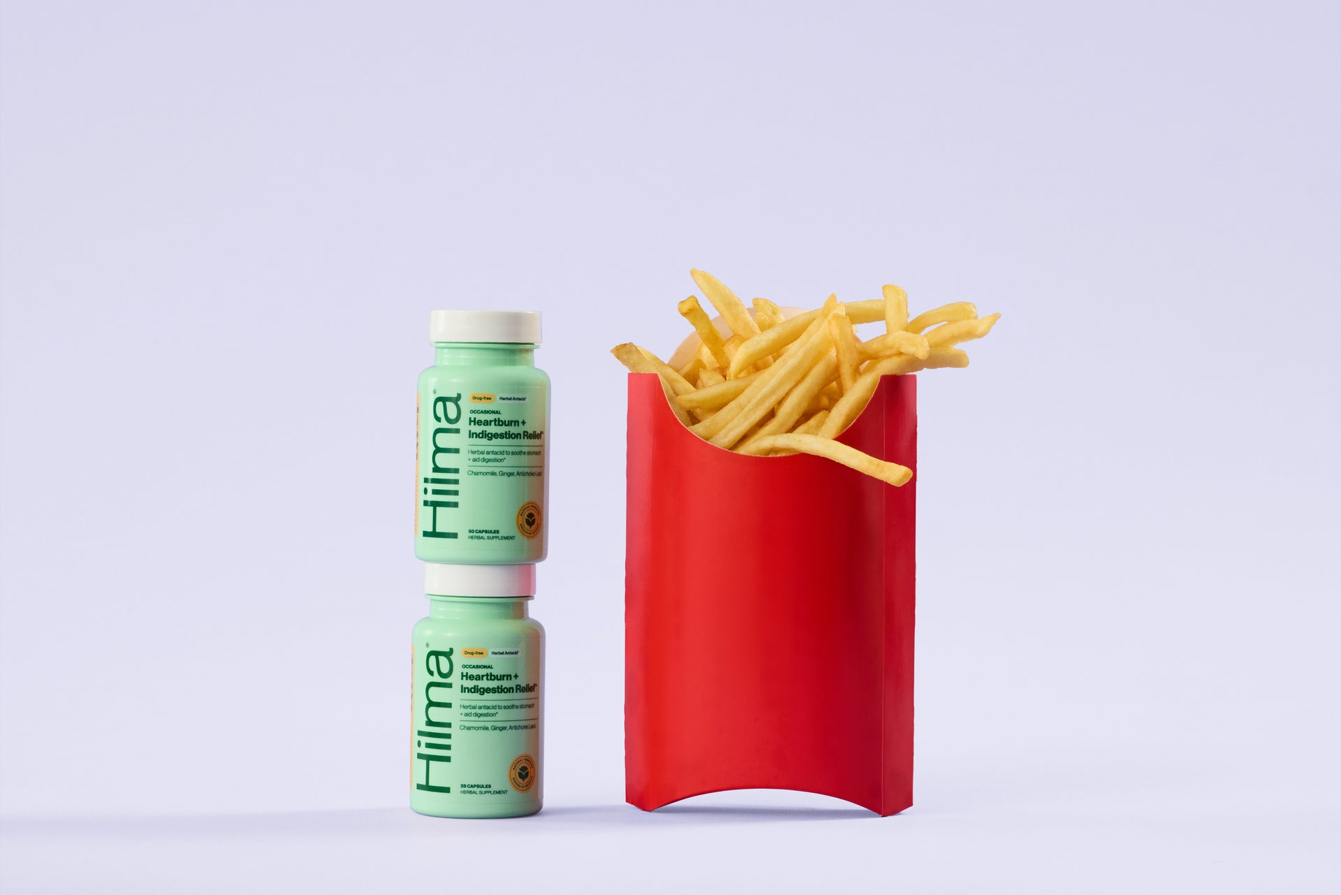 Two bottles of Hilima supplement next to a red container filled with French fries on a light gray background.