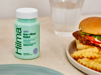 Gas + Bloat Relief next to a plate of a cheeseburger & fries