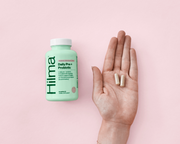 Hilma probiotic with a hand next to it holding two pills. Daily Pre + Probiotic + Herbs
