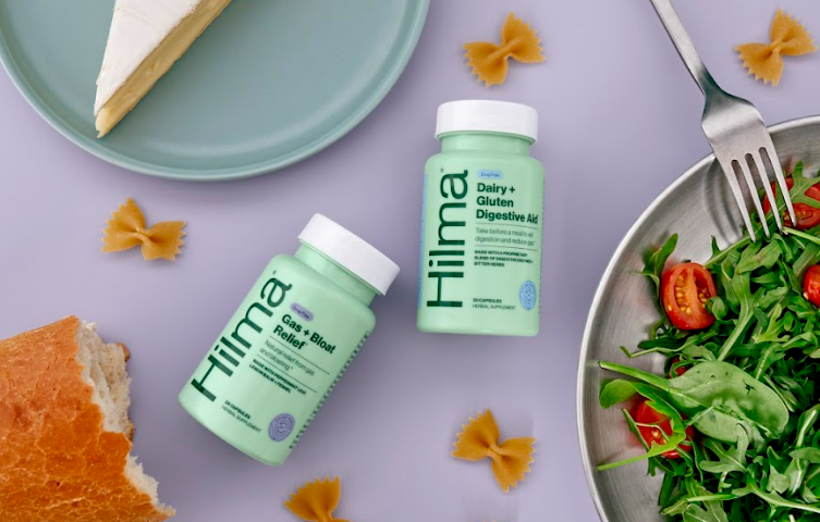 Flatlay of Gas + Bloat Relief and Dairy + Gluten Digestive Aid with a bowl of salad, brie cheese, a baguette, and bowtie pasta