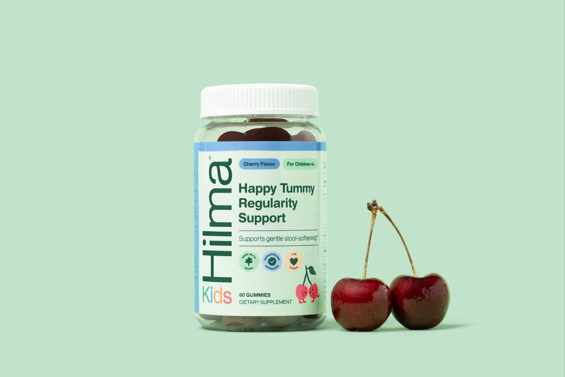 Hilma Kids Happy Tummy Regularity Support supplement bottle with two cherries on a light green background