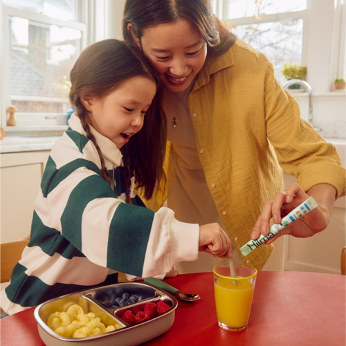Woman and child in a kitchen preparing food together.
